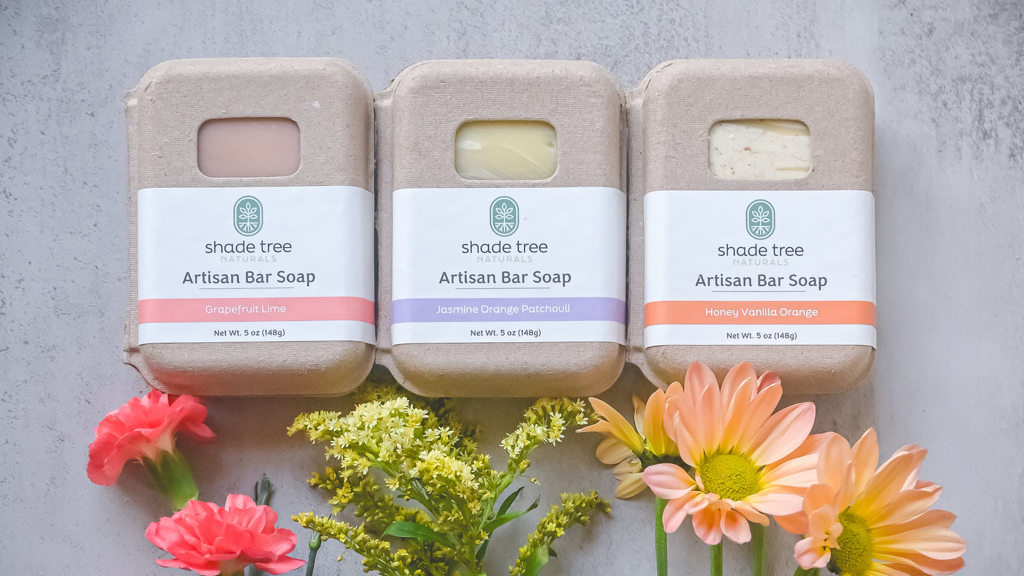 Three artisan bar soaps with flowers on a textured surface